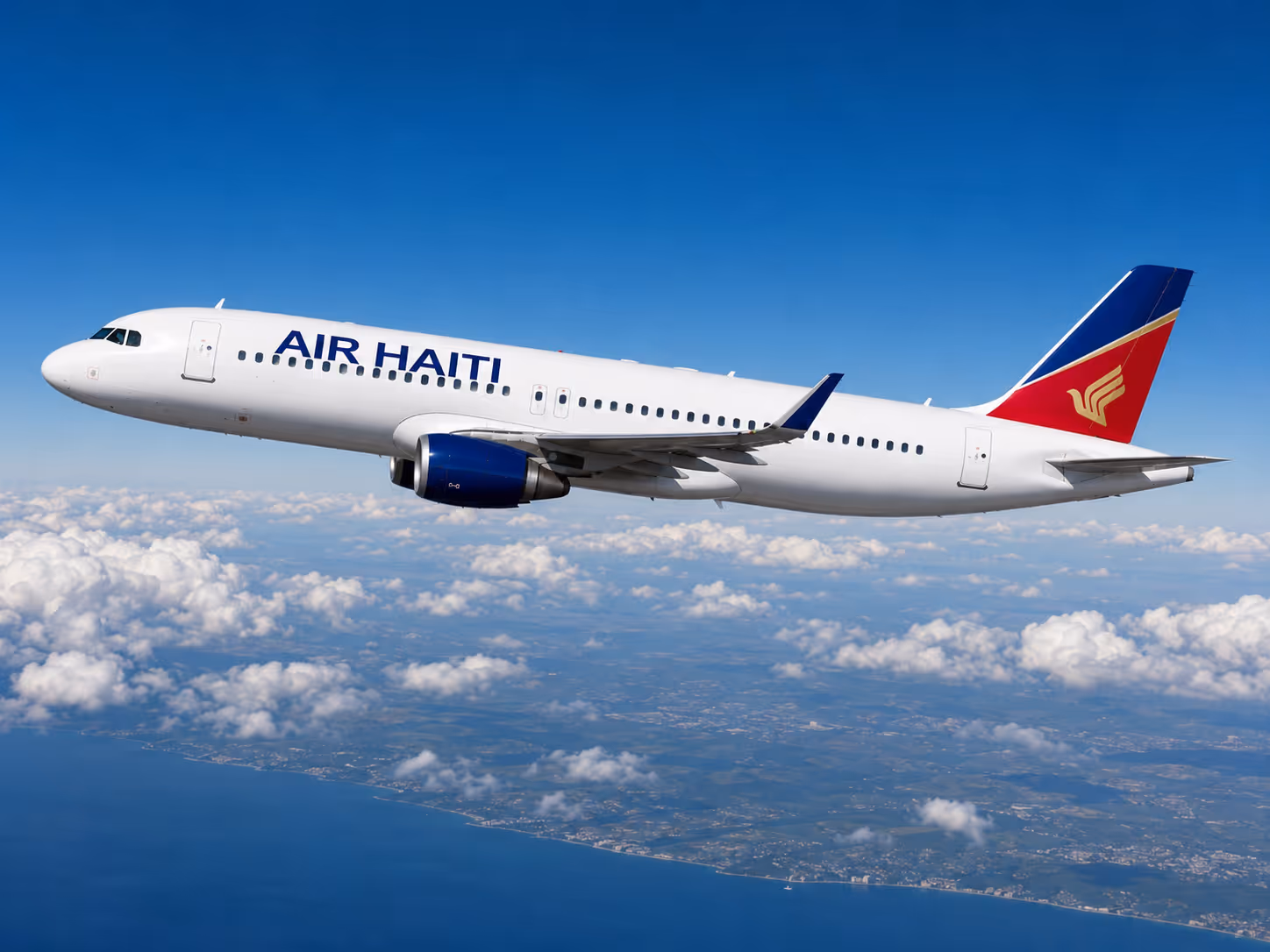 Avion d’Air Haiti survolant les nuages avec le littoral visible en dessous.